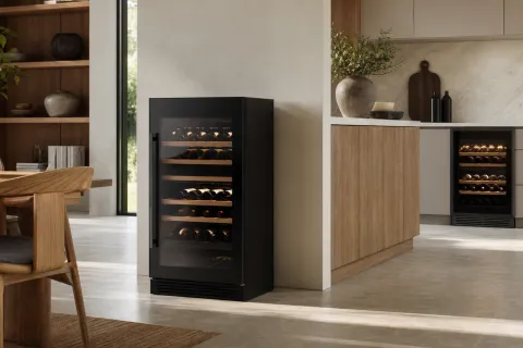 Freestanding wine fridge with open clearance beside a kitchen and a front-venting under-counter wine fridge in cabinetry